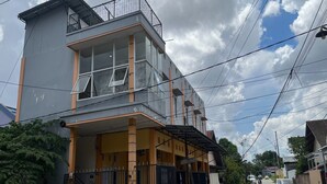 A two-story building with a balcony on the upper floor, a covered porch on the ground floor, and a gated entrance. - Hotel O Guest House Zidan 21 (Tanahgrogot)