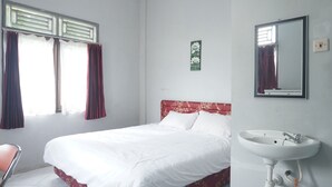 A bedroom with a bed, a window with curtains, a wall-mounted sink, and a mirror. - Hotel O Guest House Zidan 21 (Tanahgrogot)