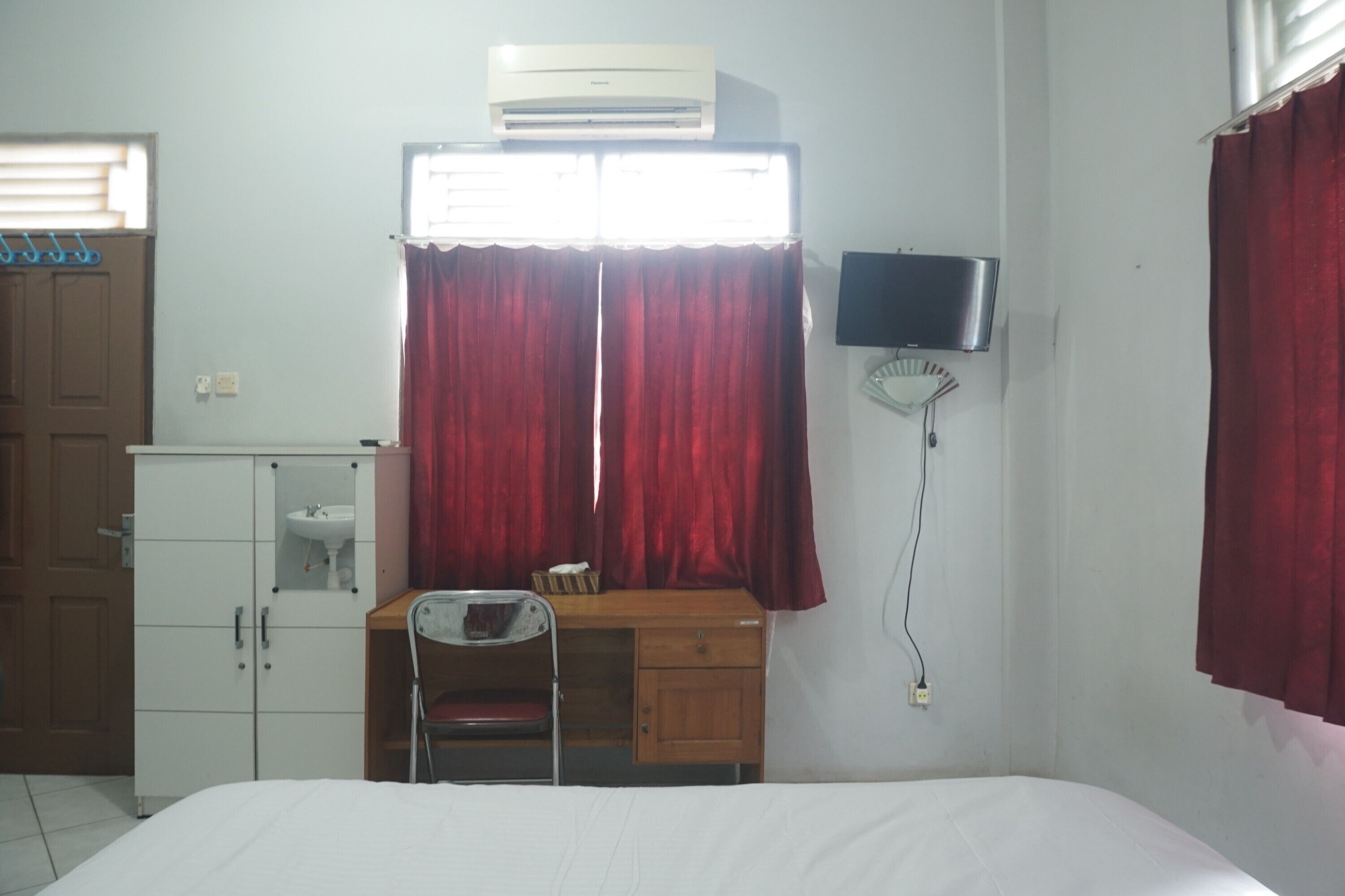 Une chambre à coucher comprenant un lit, un bureau avec une chaise, une télévision et un climatiseur.
