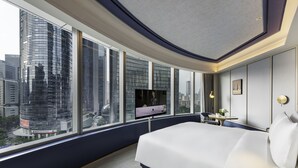 A modern hotel room with a large bed, a TV, and a view of a cityscape through large windows. - MaxX by Steigenberger Guangzhou Zhujiang New Town (Guangzhou)
