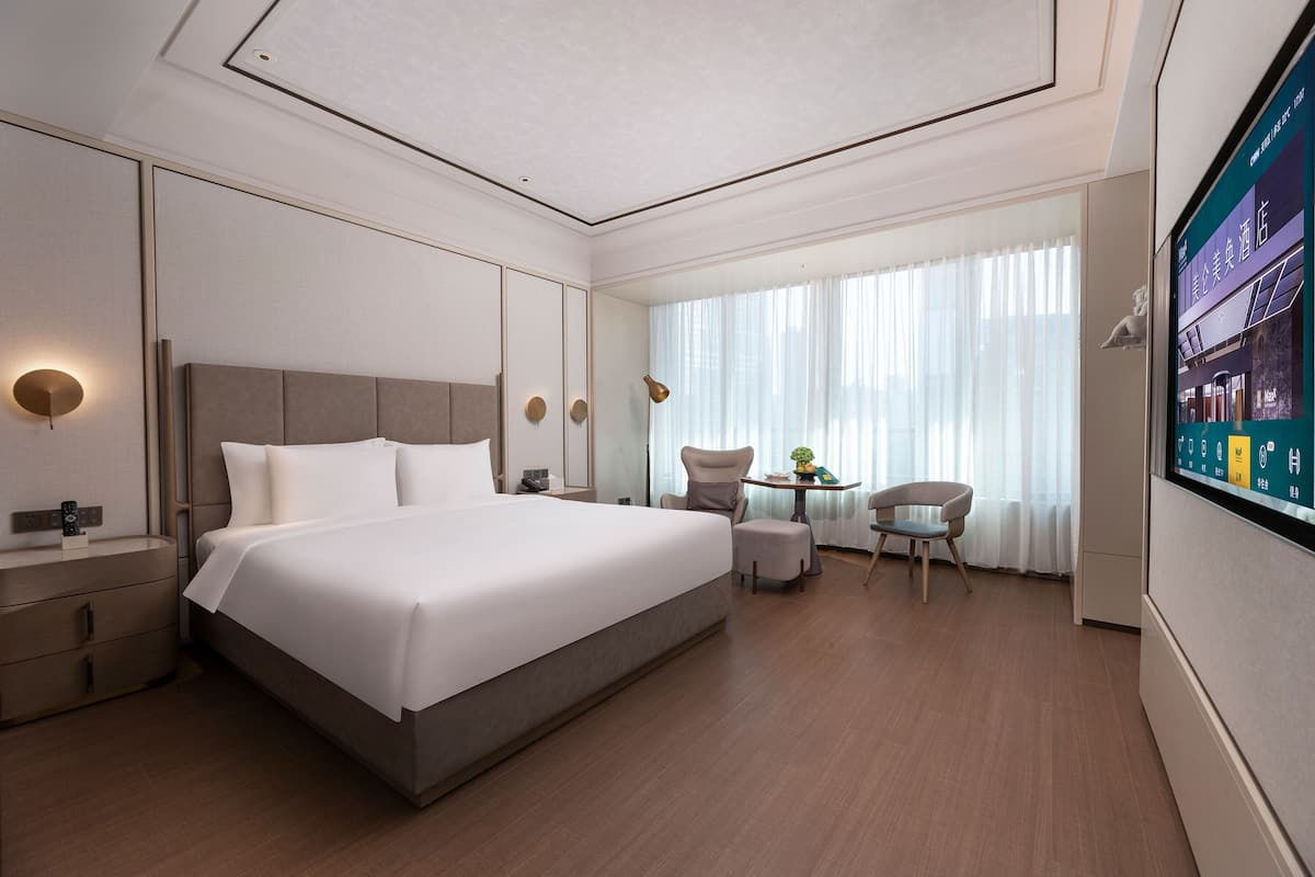 Una habitación de hotel moderna con una cama grande, mesitas de noche, un escritorio y un televisor.