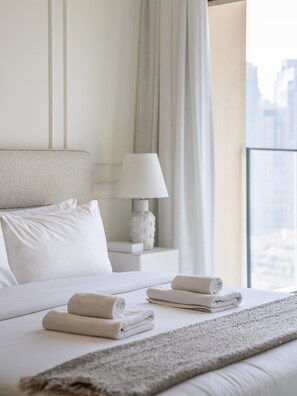 A hotel room with a neatly made bed, a bedside lamp, and a view of the city.