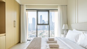 A modern hotel room with a large window, a bed with white linens, a long beige rug, and a city view. - Eloquent Upscale with Breathtaking Burj (Dubai)