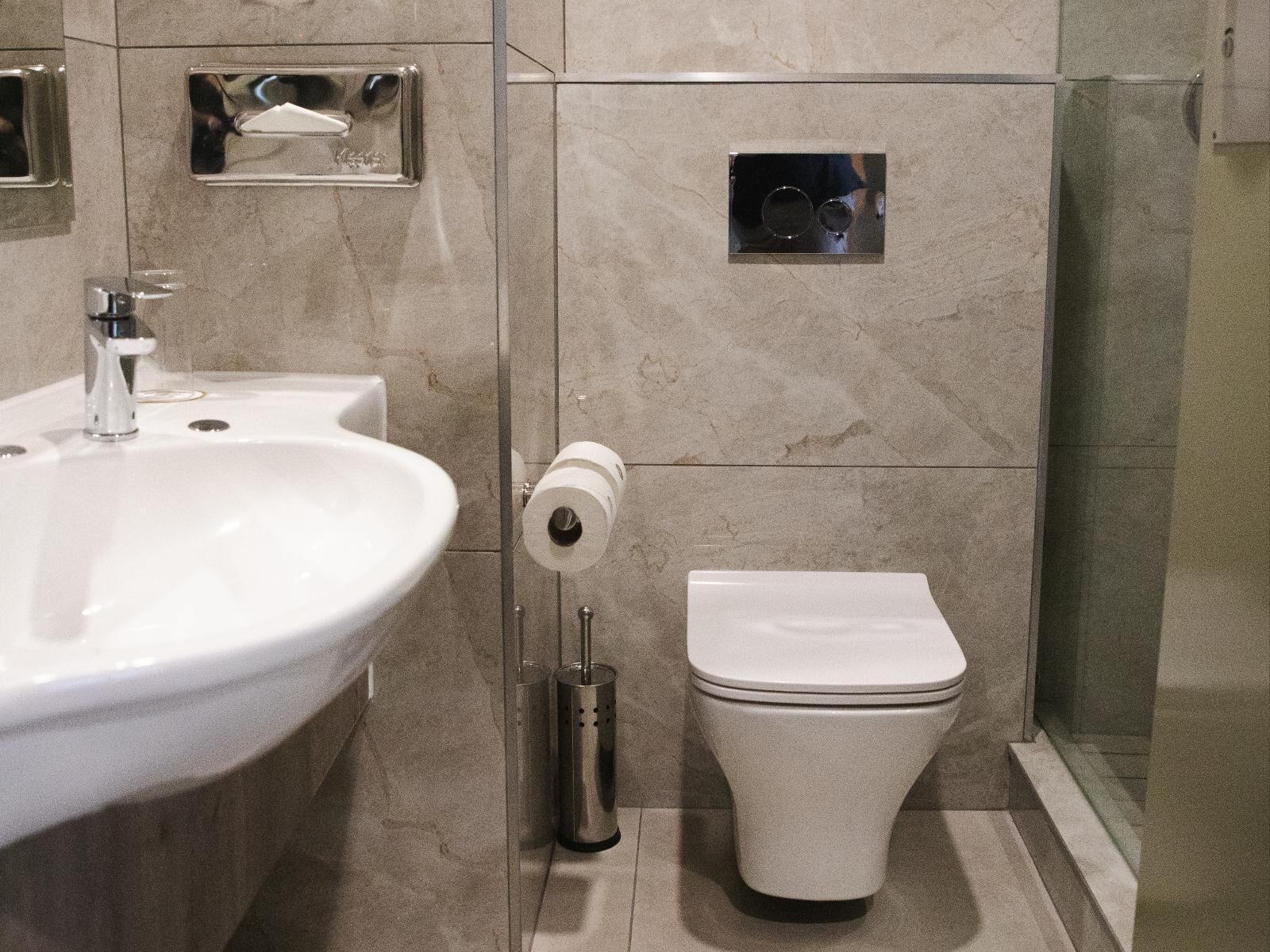 Et moderne badeværelse med vask, toilet og brusekabine i glas.