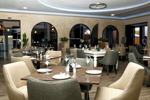 Un restaurante con mesas dispuestas para comer, sillas y una zona de bar.