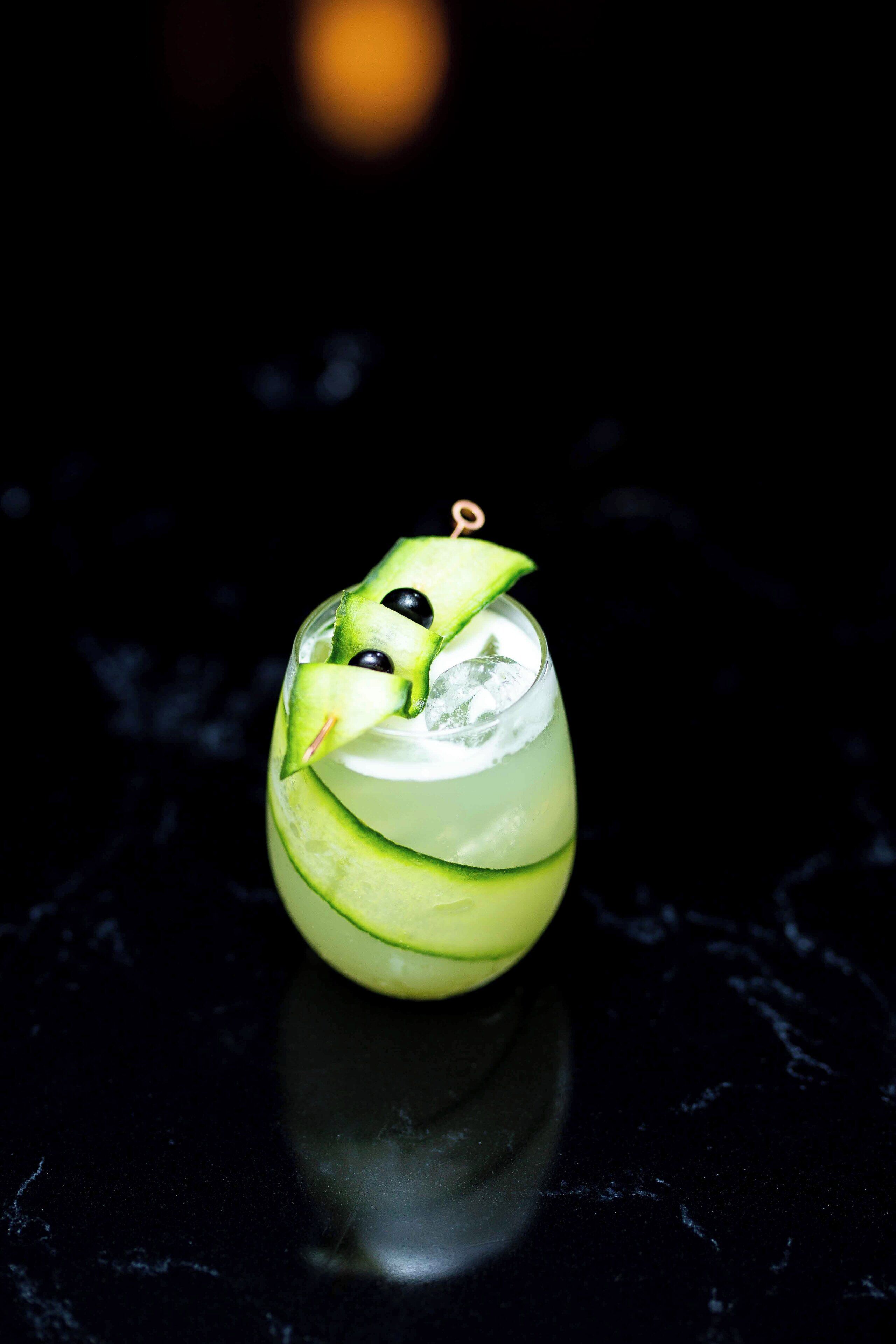 Ein Cocktail mit Limettenscheibe auf dunklem Untergrund.