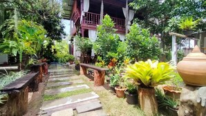A garden pathway leading to a wooden structure with a balcony. - Metha Country View Homestay Singburi (Khai Bang Rachan)