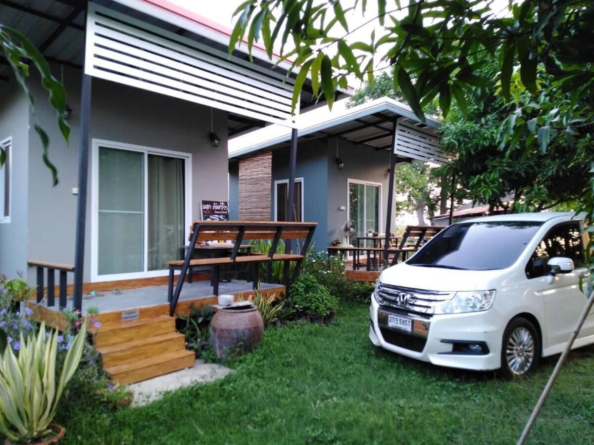 A modern house with a car parked in the driveway, a wooden bench, and a small garden area.