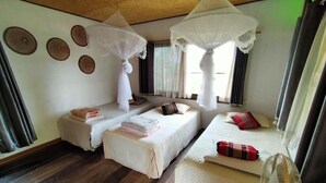 A room with three beds, each with a white bedspread and a canopy. There is a fan on the floor and a window with curtains. - Metha Country View Homestay Singburi (Khai Bang Rachan)