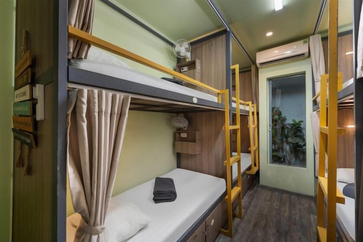 A bunk bed room with a ladder, a small desk, and a window.