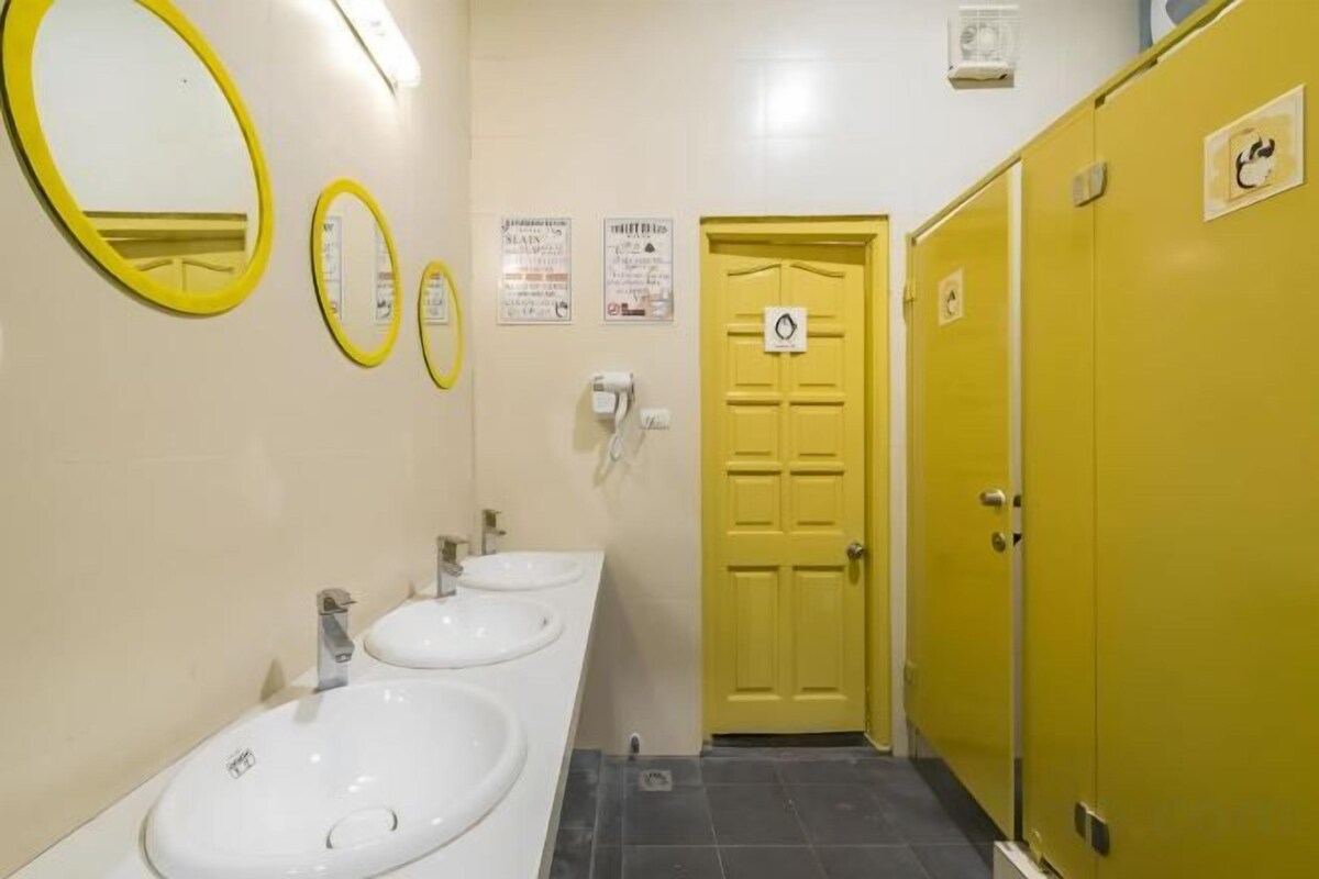 A restroom with two sinks, a yellow door, and a mirror.