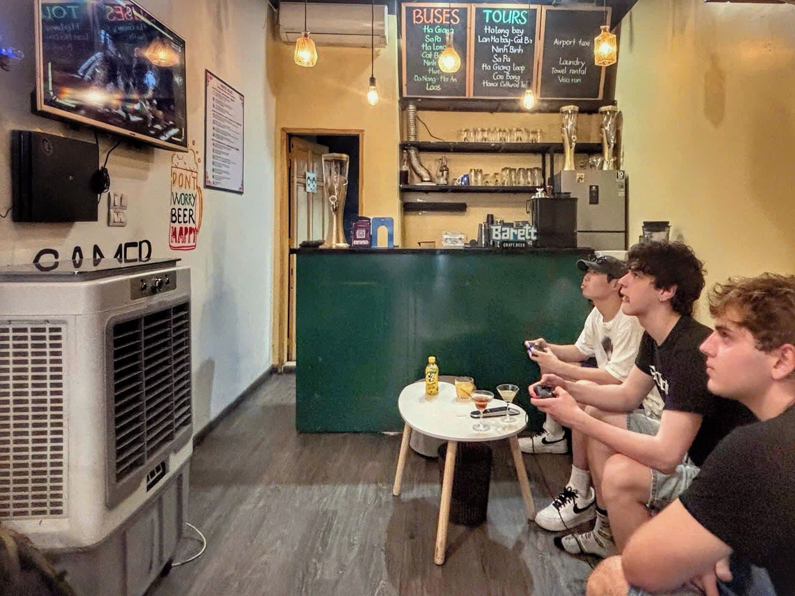 Un bar con una pantalla de televisión, una pizarra de menú y un grupo de personas sentadas en una mesa.