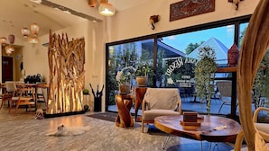 A modern interior with a large window, wooden furniture, and a decorative wall piece. - Thiptara Resort - adults only (Koh Samui)