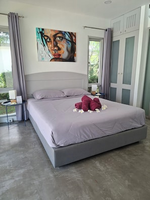Un dormitorio moderno con una cama grande, un cuadro en la pared y vistas a zonas verdes.