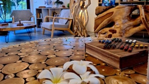 A room with a wooden table, a chessboard, and a decorative tree sculpture. There are chairs and a bookshelf in the background. - Thiptara Resort - adults only (Koh Samui)