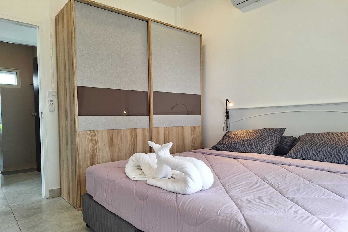 A modern bedroom with a large bed, a wooden headboard, and a sliding door.