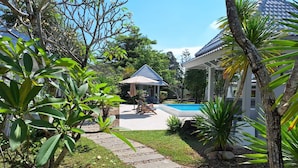 A pool area with a gazebo, surrounded by lush greenery and a clear blue sky. - Thiptara Resort - adults only (Koh Samui)