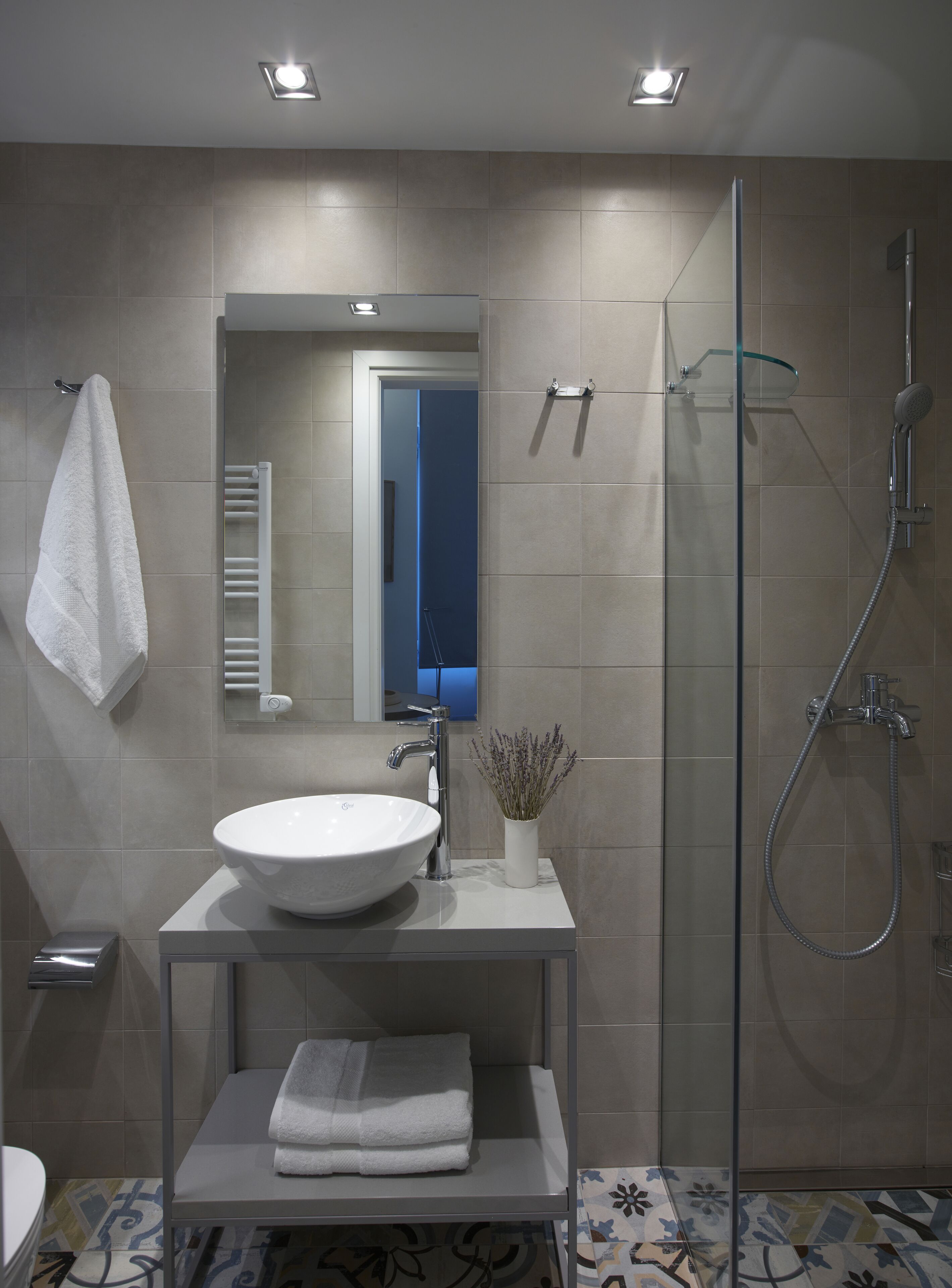 Une salle de bain moderne avec un grand lavabo blanc, une douche en verre et un porte-serviettes.