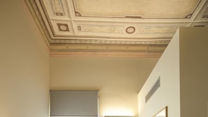 Una sala compacta con un sofá gris, una mesa redonda con un cuenco de fruta, una silla y un televisor sobre un mueble.