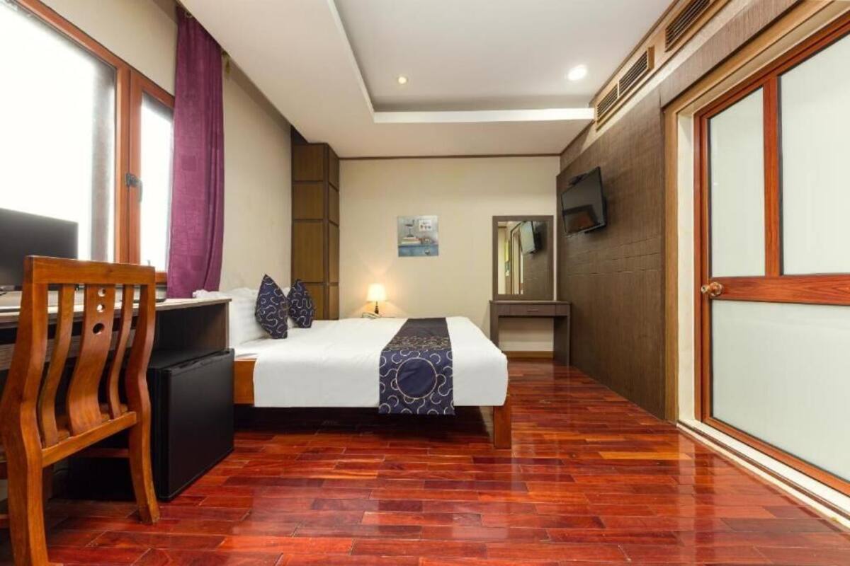 Ein Hotelzimmer mit einem Bett, einem Schreibtisch mit Stuhl, einem Fernseher und einem kleinen Kühlschrank.