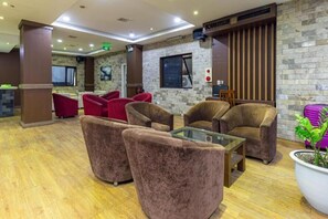 A lobby with plush seating, a reception desk, and a stone wall. - Dream Hotel by Bay Luxury (Hanoi)