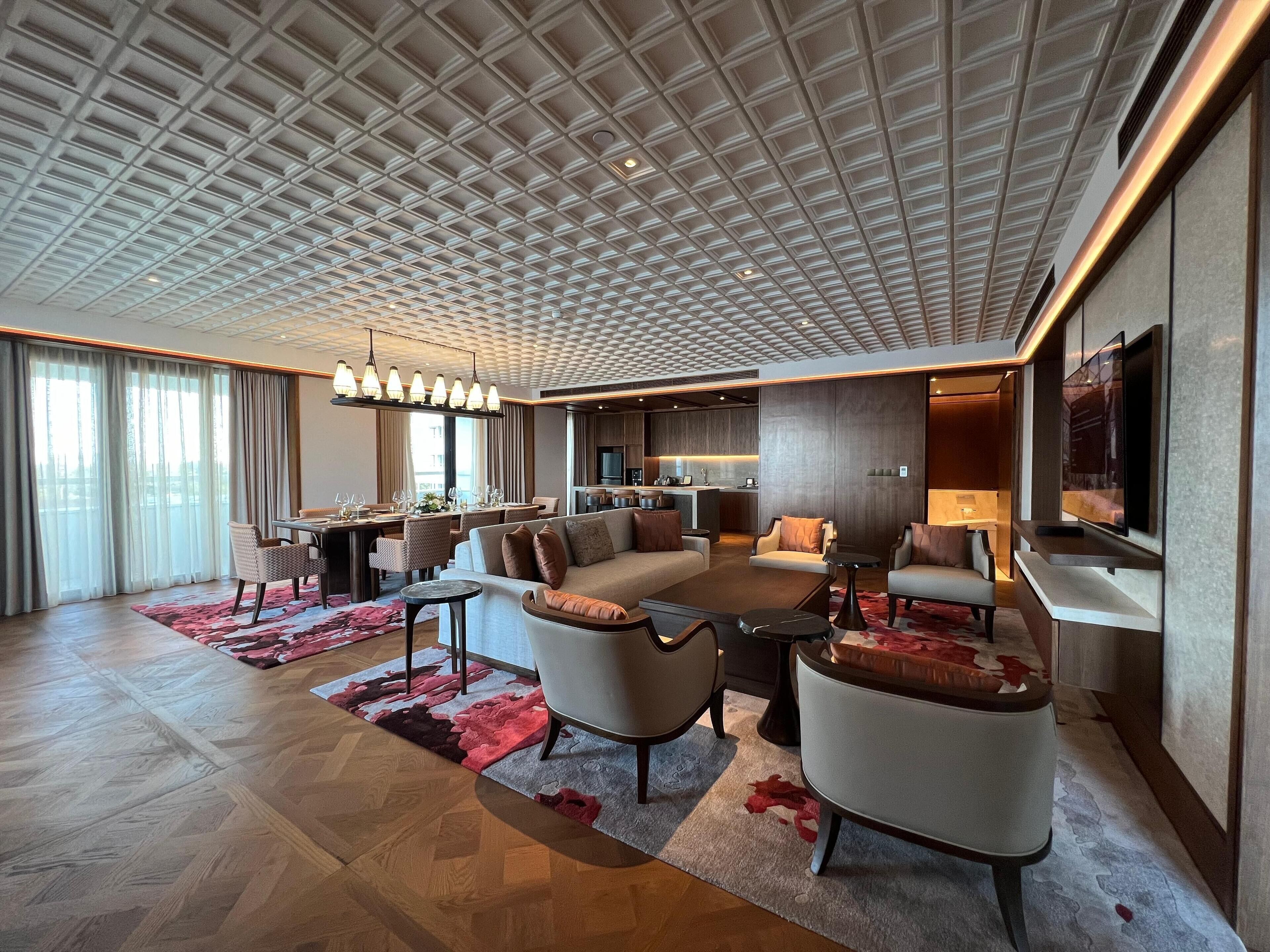 A modern hotel lobby with a dining area, sofas, and a TV.