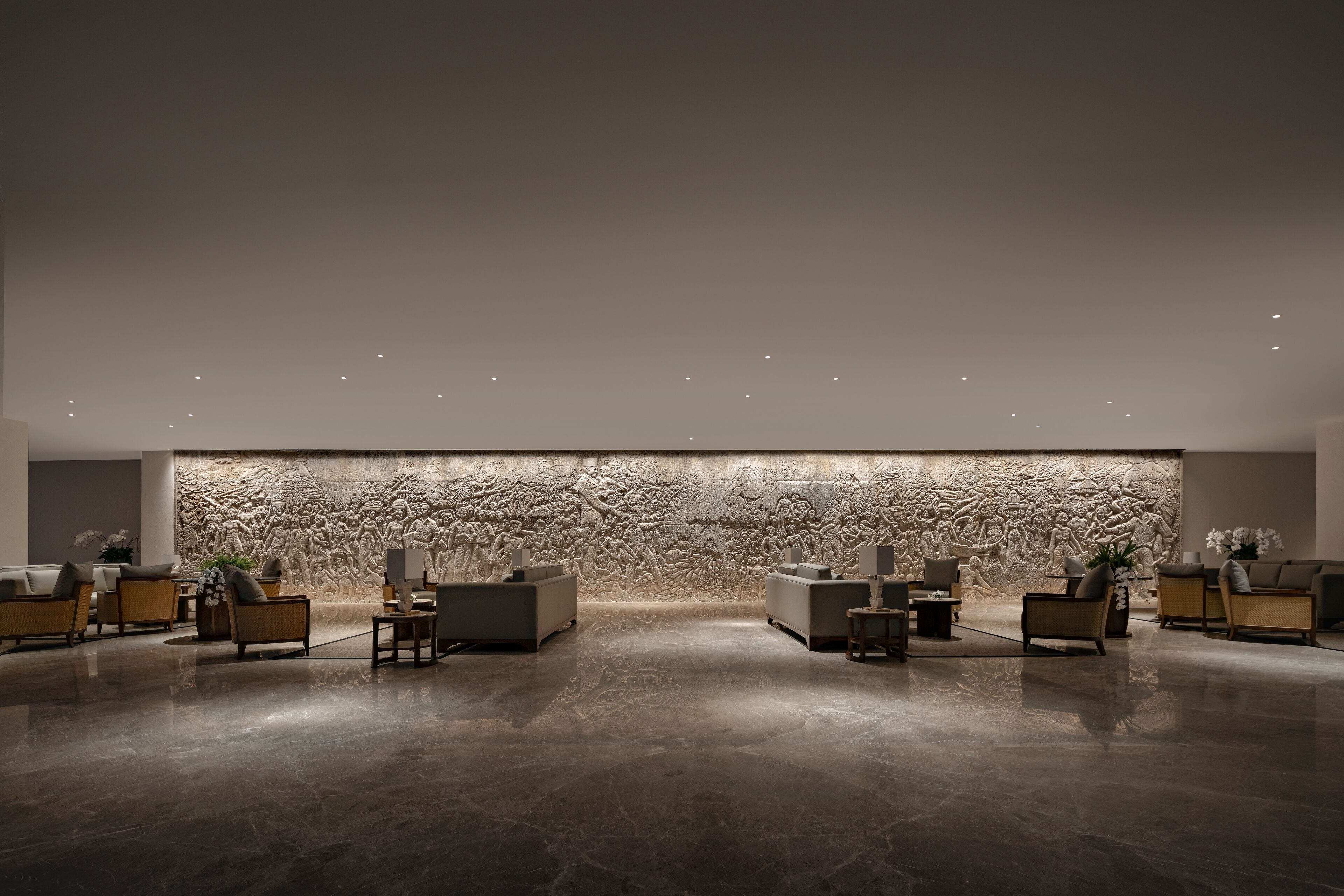A modern lobby with a stone wall mural, seating area, and polished floor.