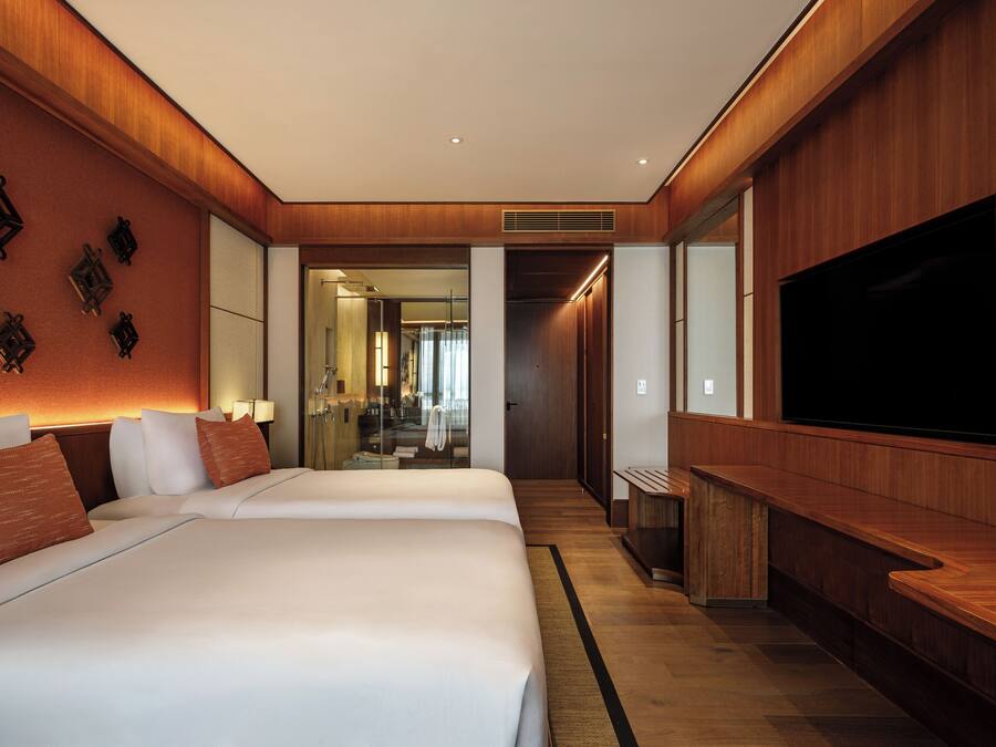Habitación de hotel con dos camas, un televisor y un espejo.