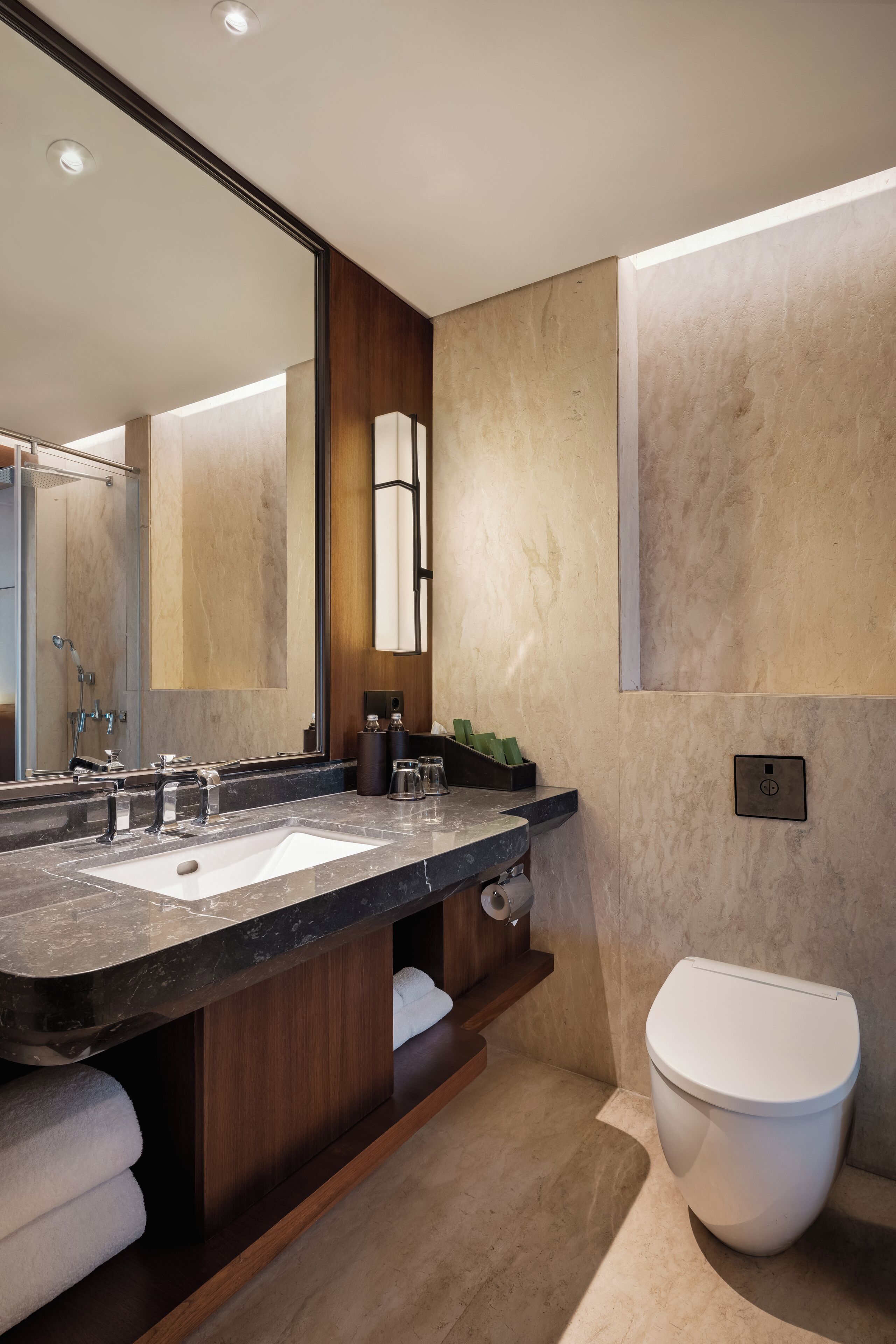 Un baño moderno con un espejo grande, lavamanos dobles y un inodoro.