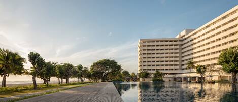 A hotel with a pool, wooden deck, and a view of the ocean.