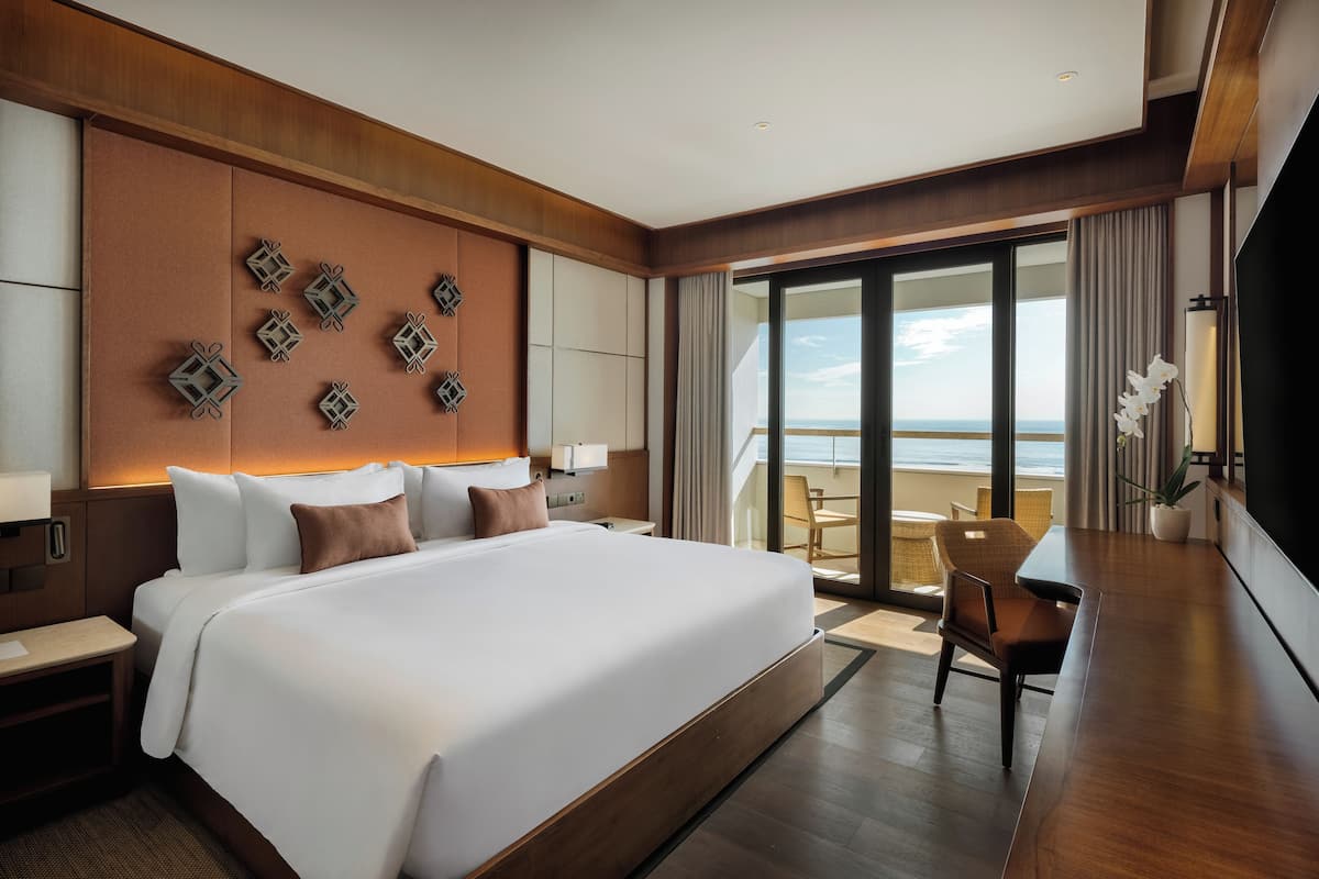 A modern hotel room with a large bed, a balcony with a view, and a dining area.