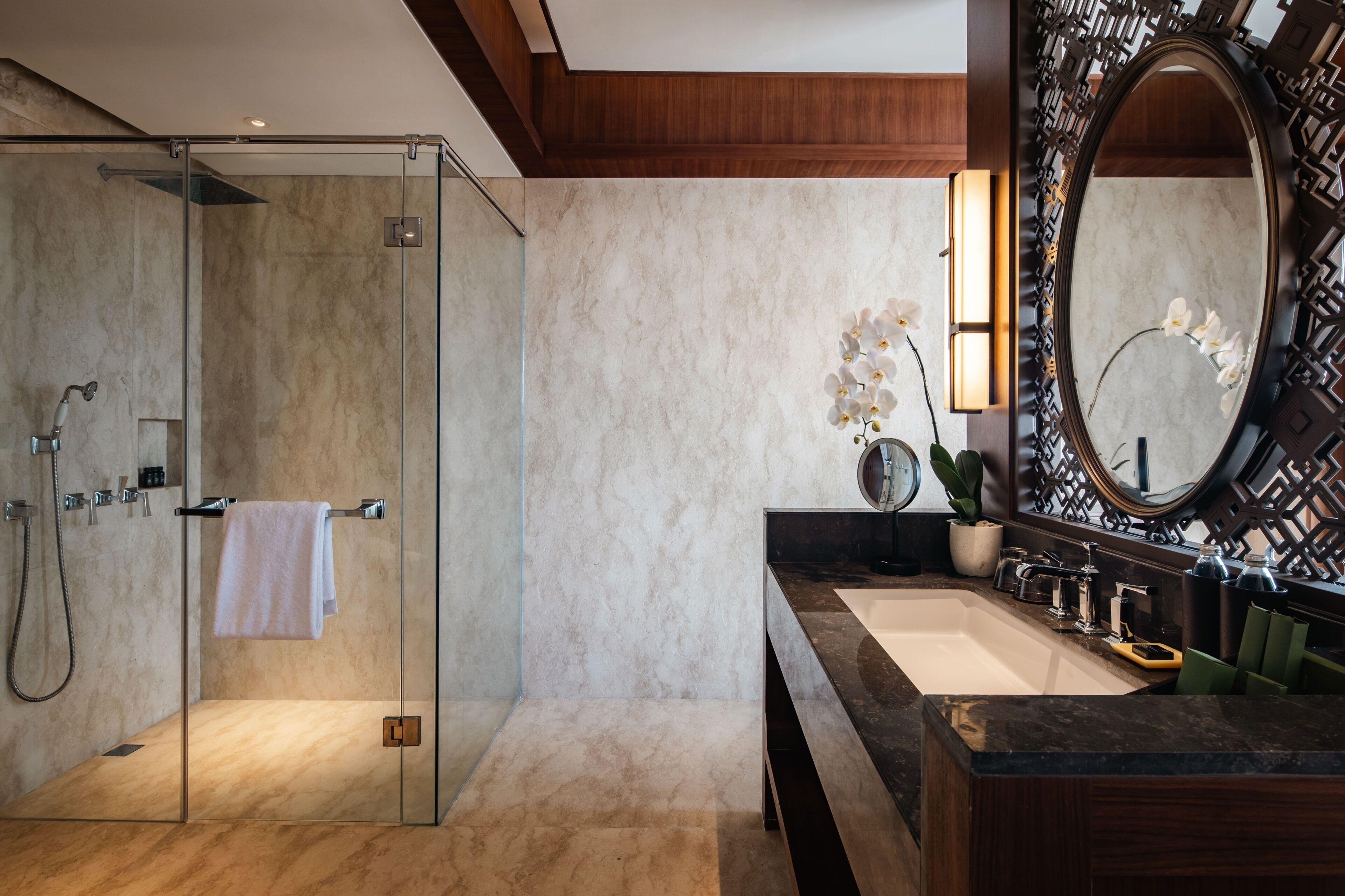 Un baño moderno con ducha de vidrio, un espejo grande y encimera de mármol.