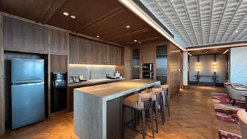 A modern kitchen with a central island, built-in appliances, and a bar area with stools.
