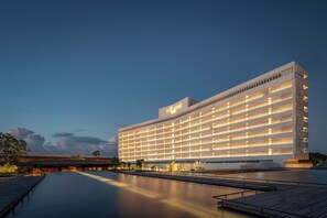 Un hotel moderno con techo plano, varios pisos y una amplia zona de piscina.