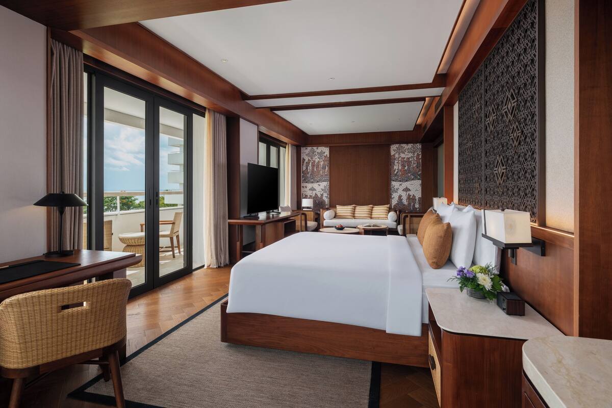 A hotel room with a large bed, a television, a desk, and a view of the outdoors.