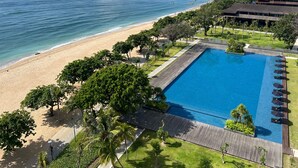 Vista aérea de un resort con una gran piscina, playa y exuberante jardinería.