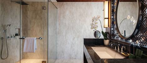 A modern bathroom with a glass-enclosed shower, a large mirror, and a marble countertop.