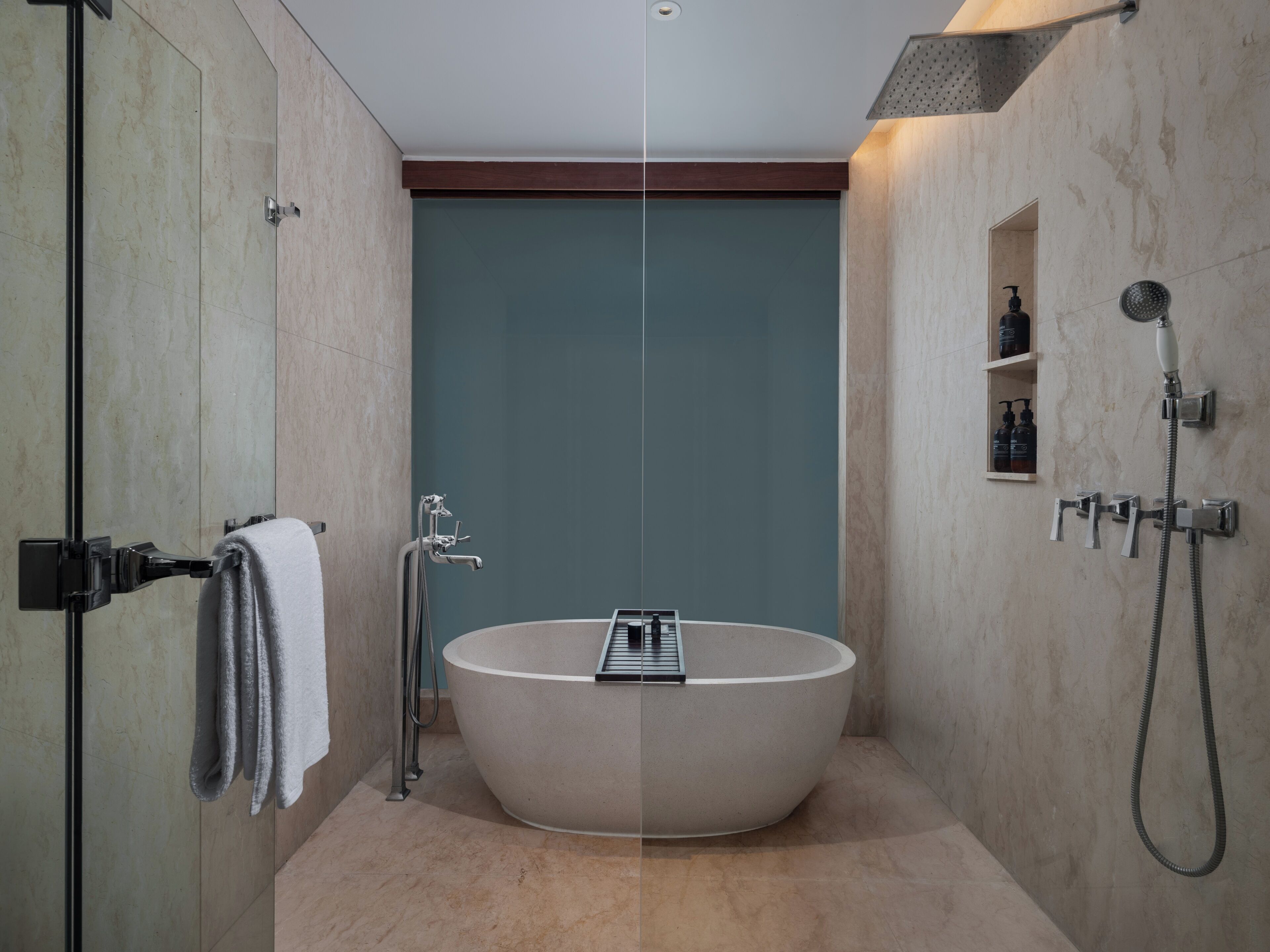 Ein modernes Badezimmer mit einer freistehenden Badewanne, einer Duschkabine aus Glas und einer integrierten Ablage mit Pflegeprodukten.
