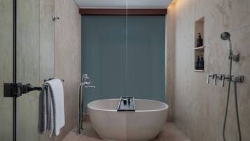 Ein modernes Badezimmer mit einer freistehenden Badewanne, einer Duschkabine aus Glas und einer integrierten Ablage mit Pflegeprodukten.