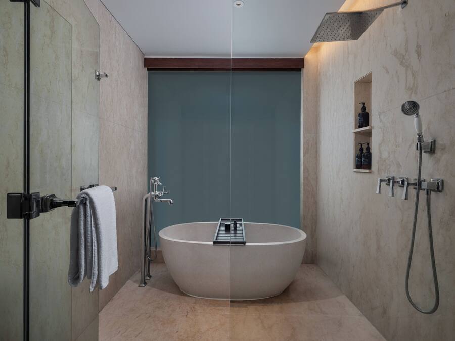 Ein modernes Badezimmer mit einer freistehenden Badewanne, einer Duschkabine aus Glas und einer integrierten Ablage mit Pflegeprodukten.