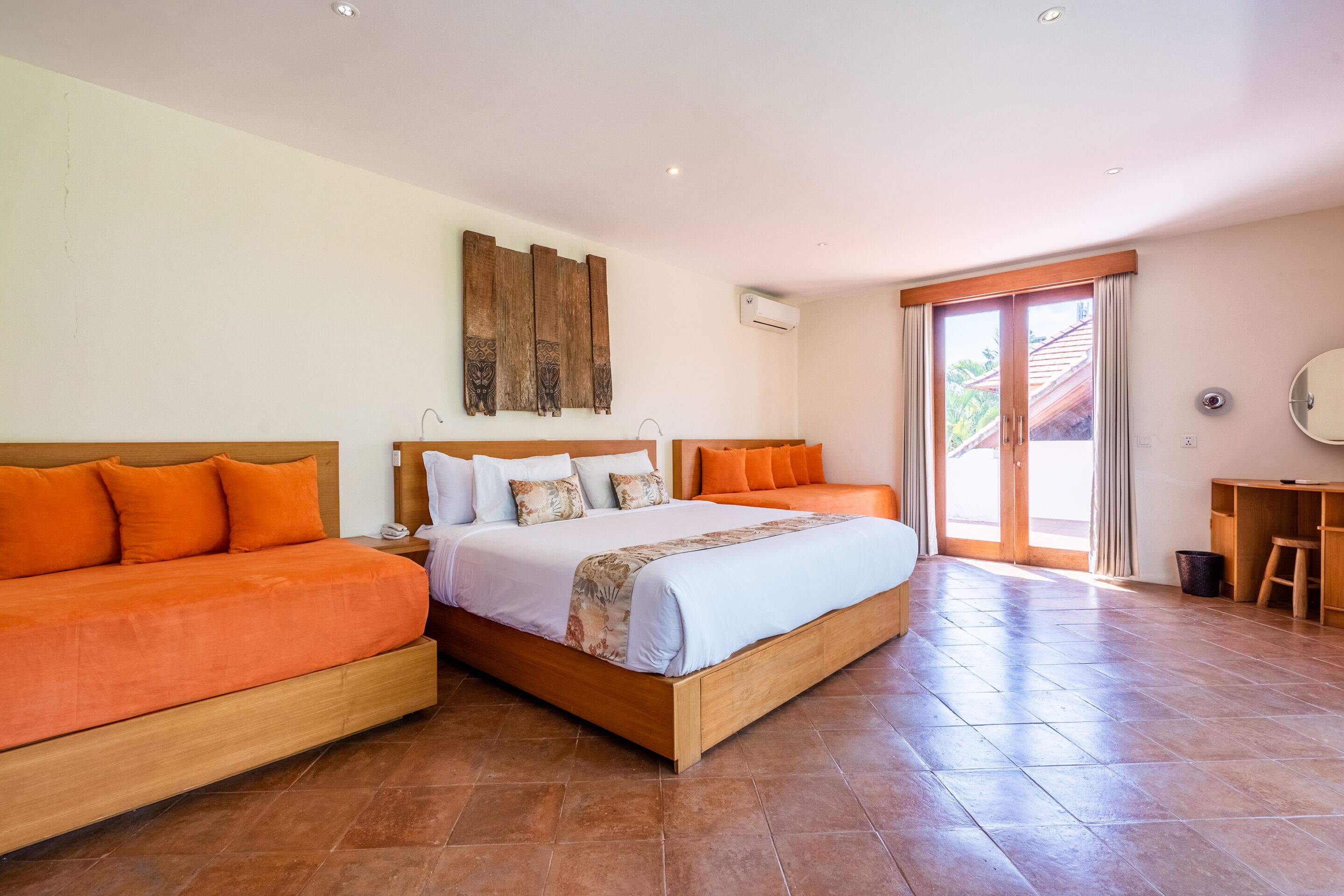 A spacious bedroom with a large bed, two side beds, and a wooden headboard.