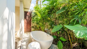 Une baignoire sur pied, installée dans un jardin luxuriant.