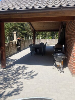 Eine Terrasse im Freien mit Ziegelwand, Grill und Tisch mit Stühlen.