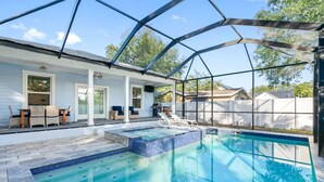 A pool area with a glass enclosure, lounge chairs, and a covered patio. - Luxury Retreat • Hot Tub • Private Fenced Yard (Tampa)