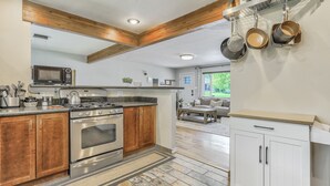 A modern kitchen with wooden cabinets, stainless steel appliances, and hanging pots.