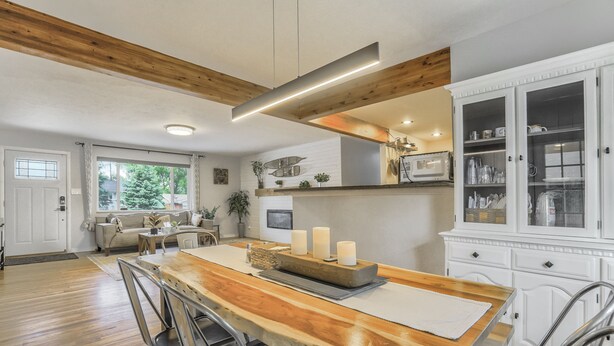 A spacious kitchen with a wooden dining table, white cabinetry, and a large window.