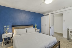 A bedroom with a bed, nightstand, dresser, and a potted plant. - Mid-Evening Star (Colorado Springs)