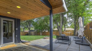 A patio with stone flooring, outdoor furniture, and a wooden ceiling.