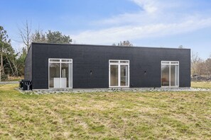 A modern, single-story building with a dark exterior, large windows, and a flat roof.
