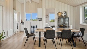 Une cuisine spacieuse avec un lambris en bois, un coin repas avec une table et des chaises, et une vue sur l’extérieur.